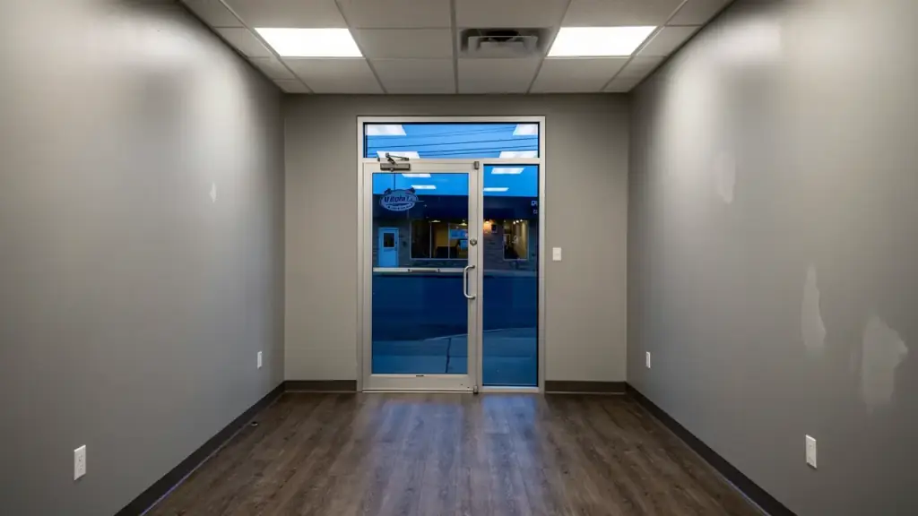 Illustration of a small storefront office interior with new LED ceiling panels and a glass entry door